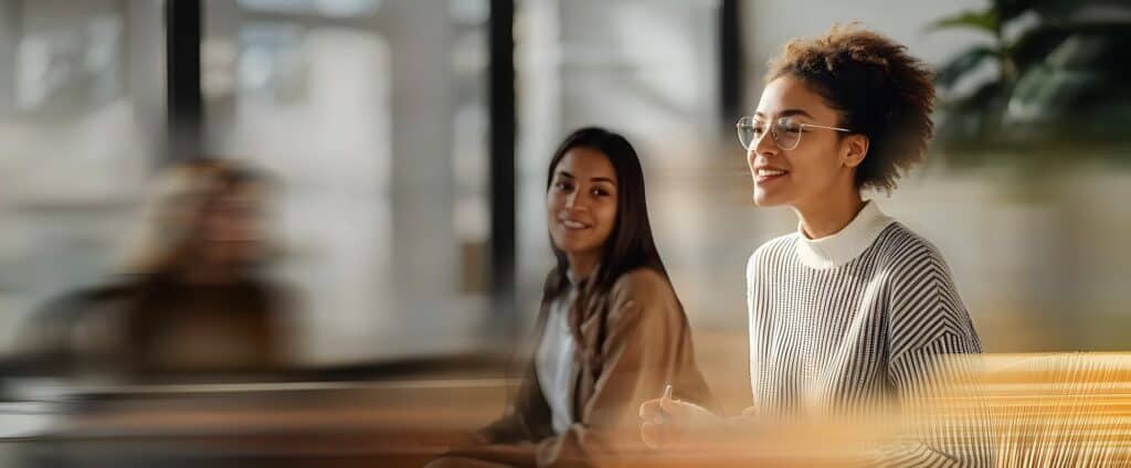 Dos mujeres en un entorno de aprendizaje moderno, participando activamente en una formación sobre inteligencia artificial. Representación del programa AI Skills 4 Women.