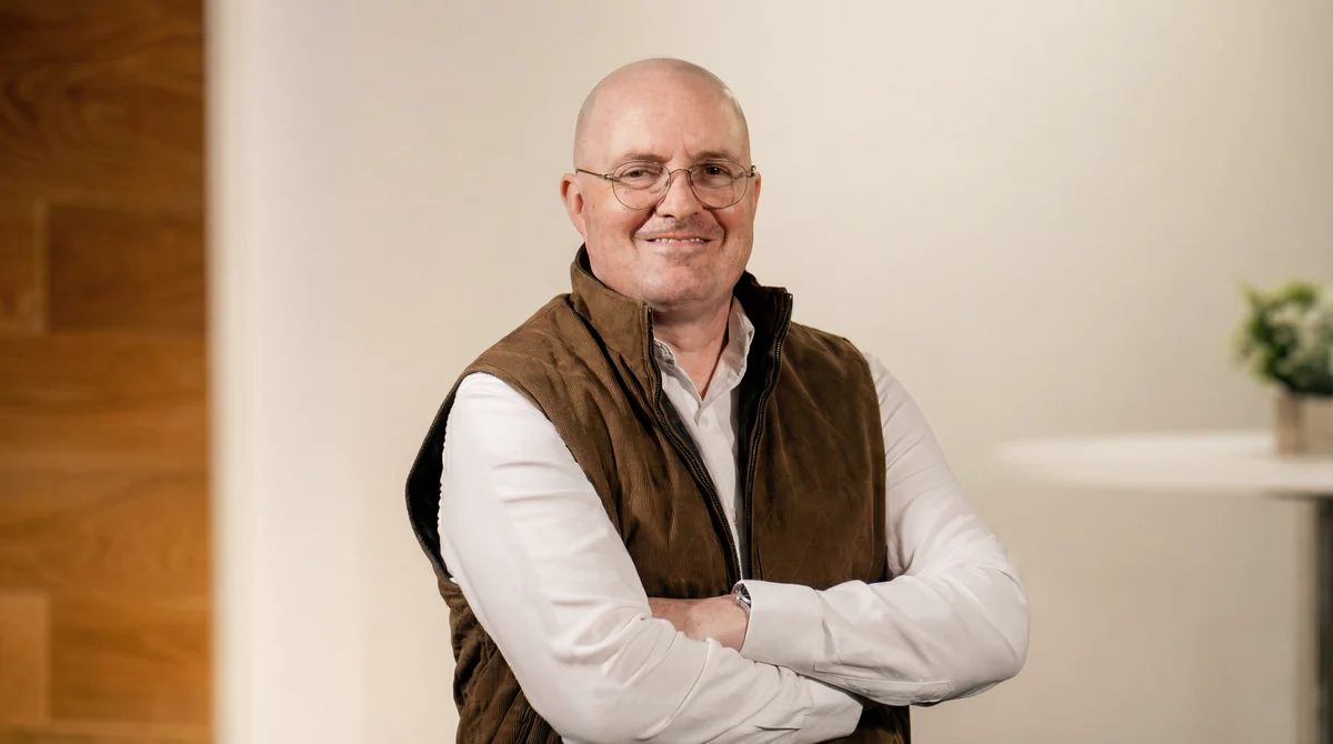 Gerardo Kerik smiling with arms crossed, wearing glasses and a brown vest