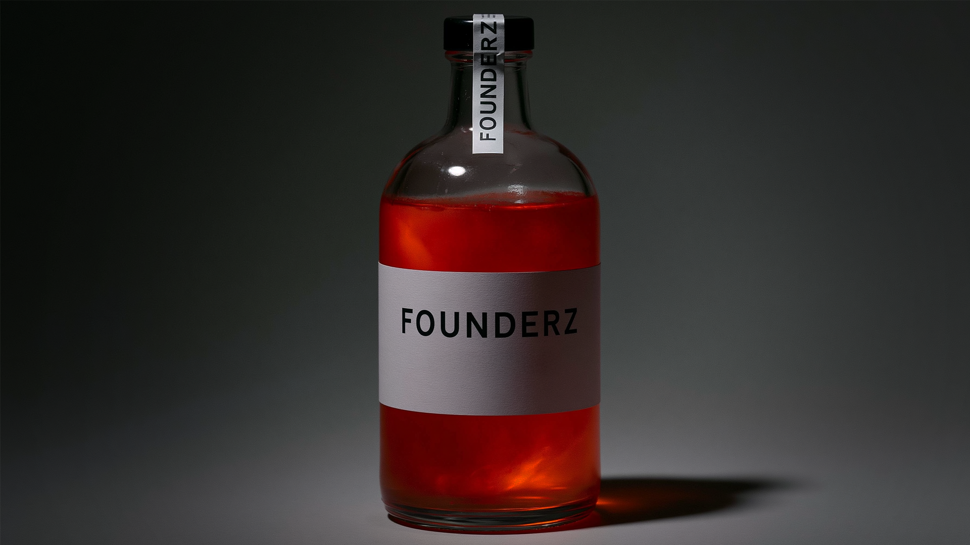 Botella de vidrio con líquido rojo y etiqueta Founderz sobre fondo gris oscuro