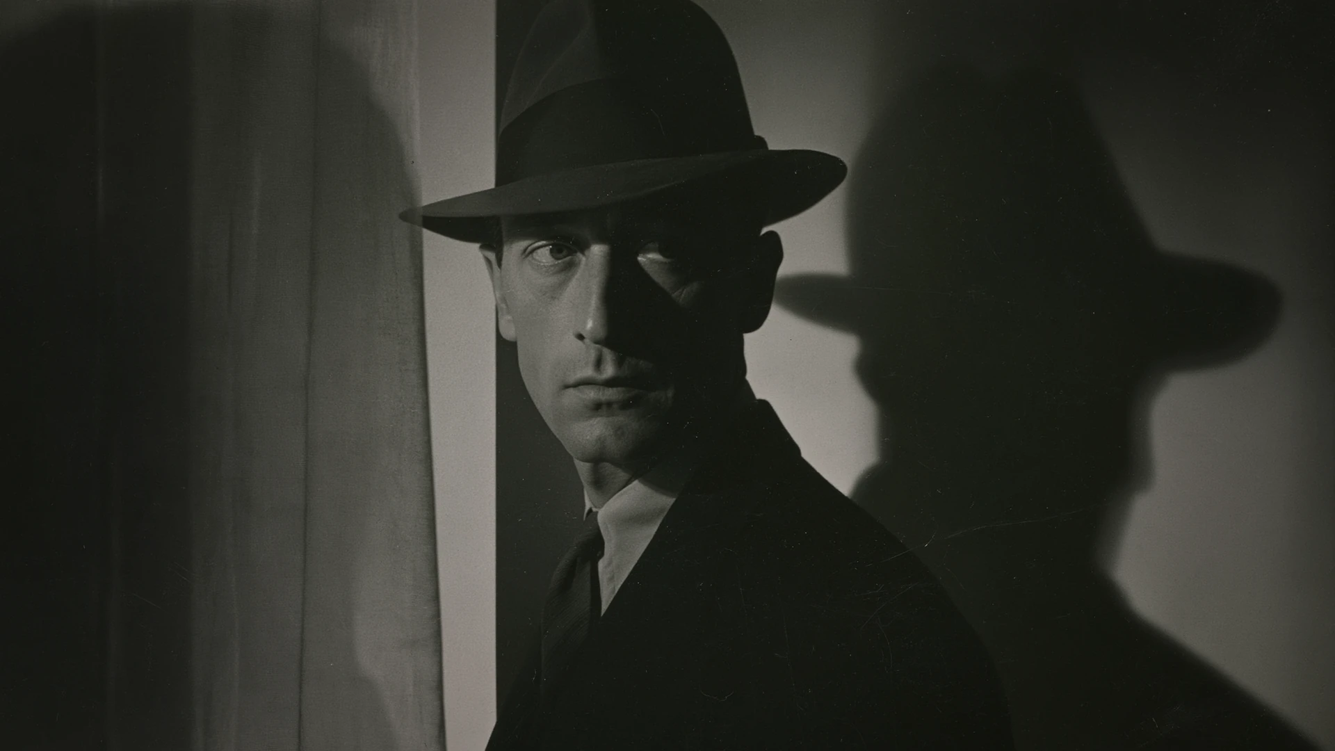 Retrato fotográfico noir de hombre con sombrero y sombra proyectada