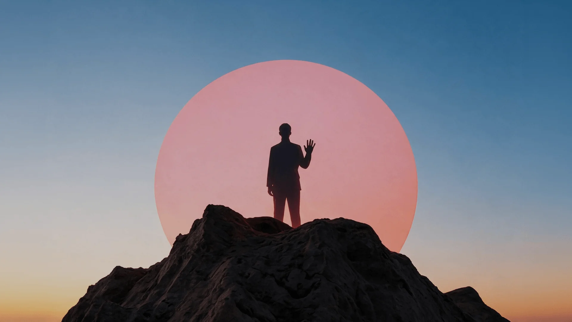 Silhouetted man waving from a rocky peak before a large pink sun