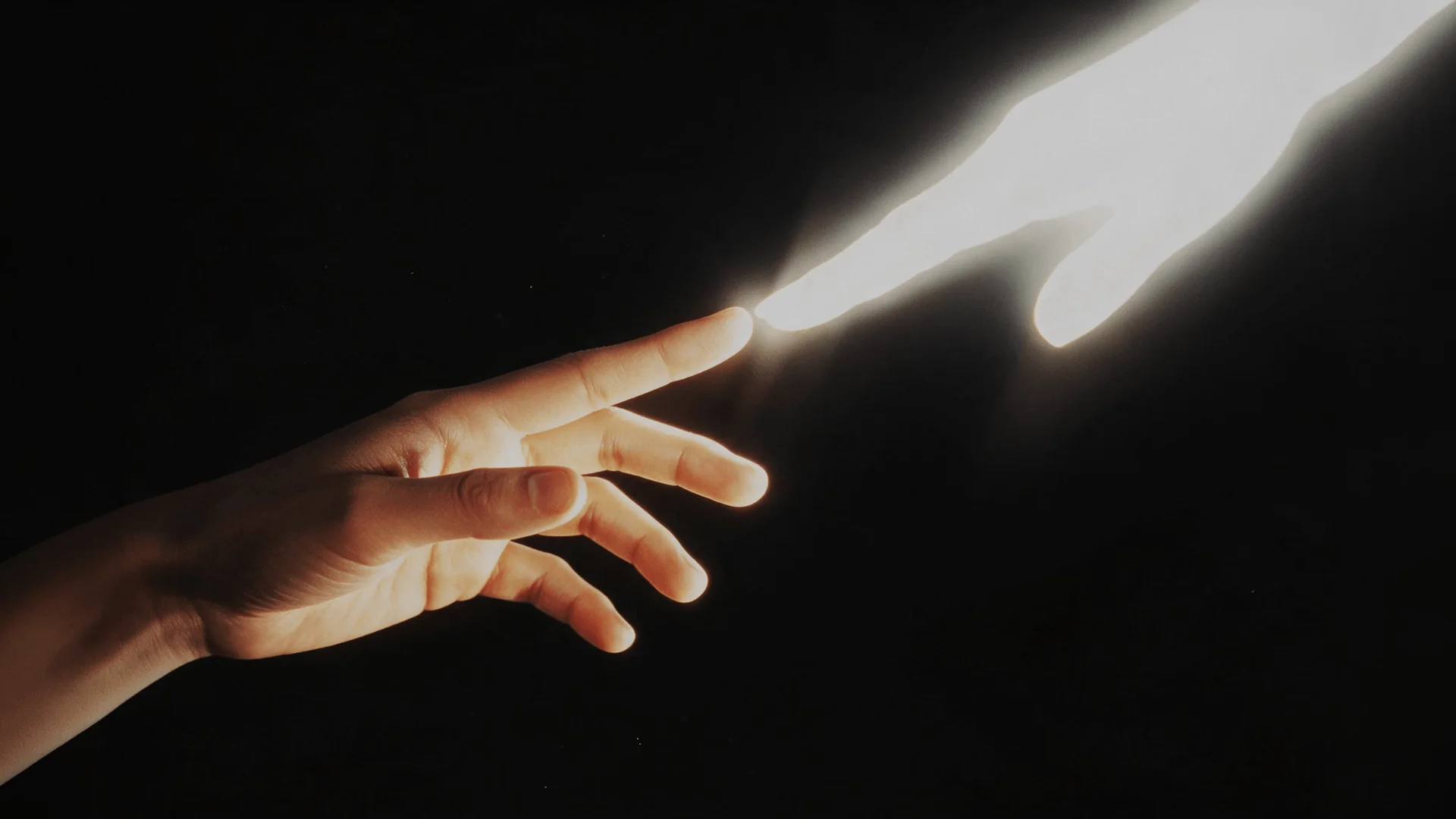 Human hand touching fingertips with a glowing hand against black background